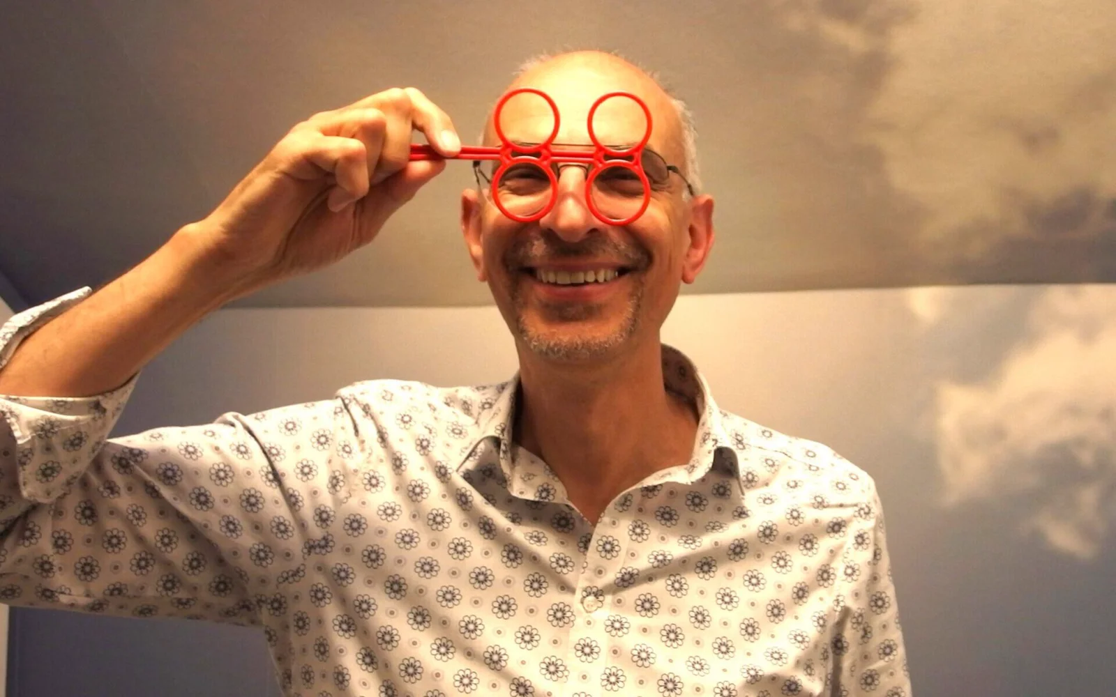 Thomas lacht mit einer roten Scherzbrille in der Hand